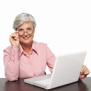 woman with gray hair and glasses using a computer