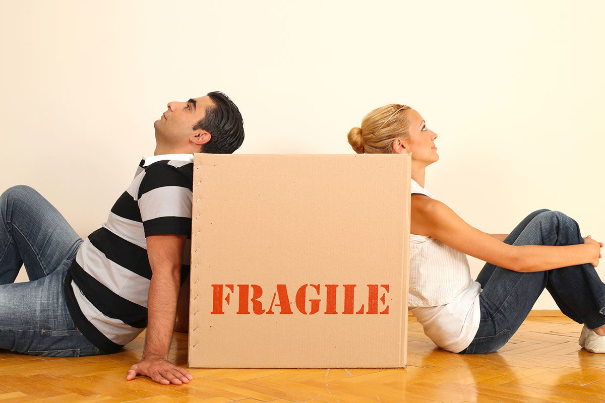 man and woman sitting next to a moving box.