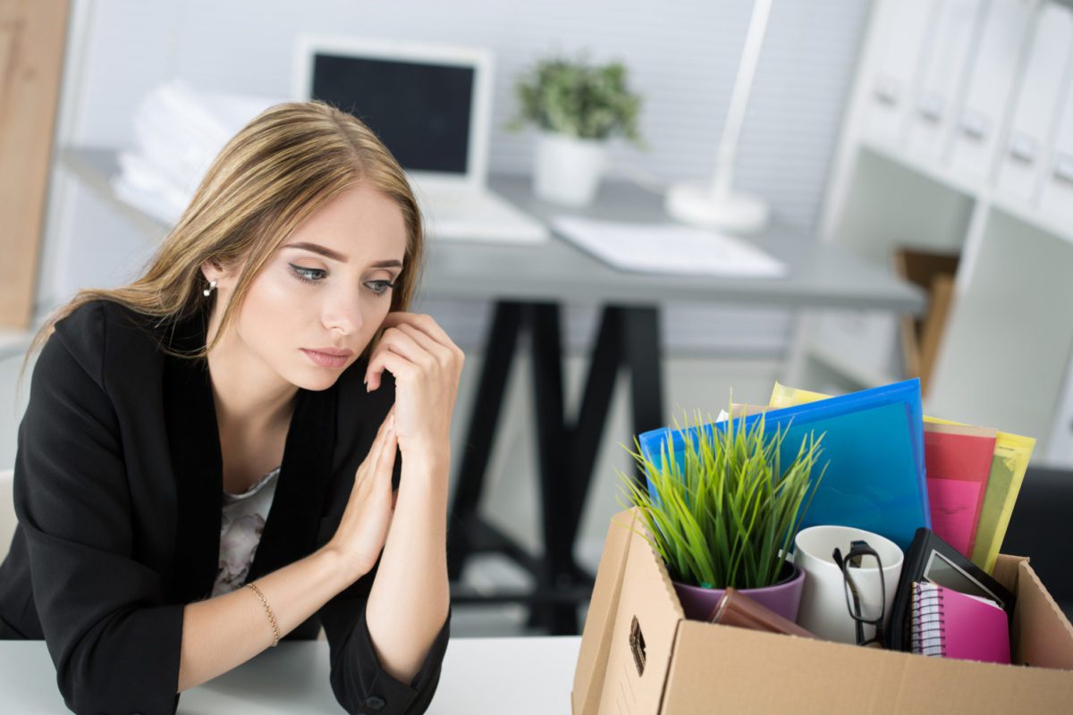 dismissed female worker in office sitting near carton box