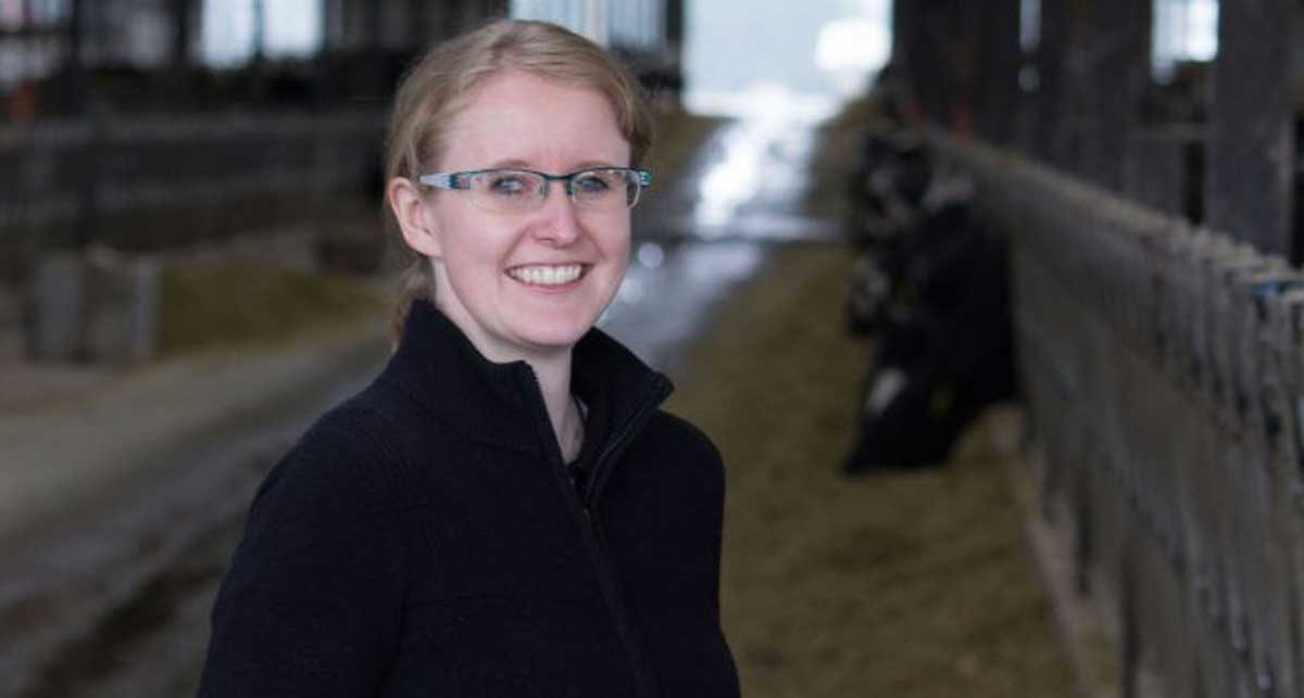 woman smiling in a barn with cows in the background