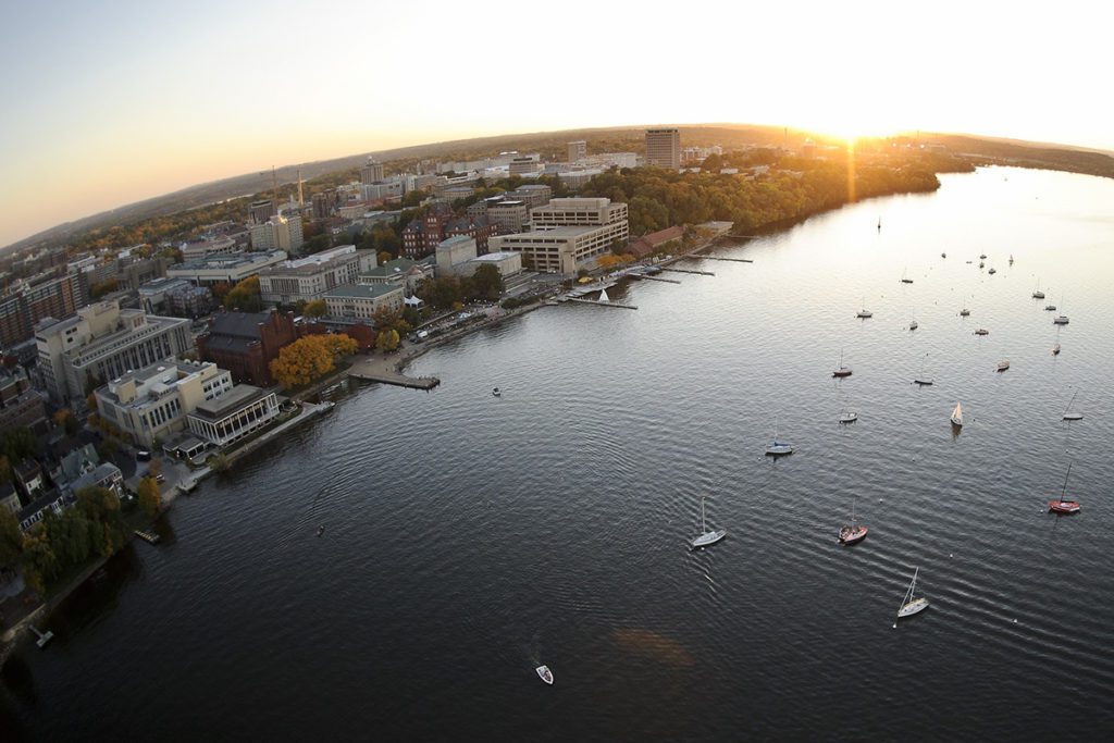 Boats dot Lake Mendota in a fisheye-lens aerial view of the University of Wisconsin-Madison campus during an autumn sunset.