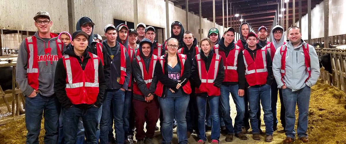 Farm and Industry Short Course students stand in the cow barn as a group