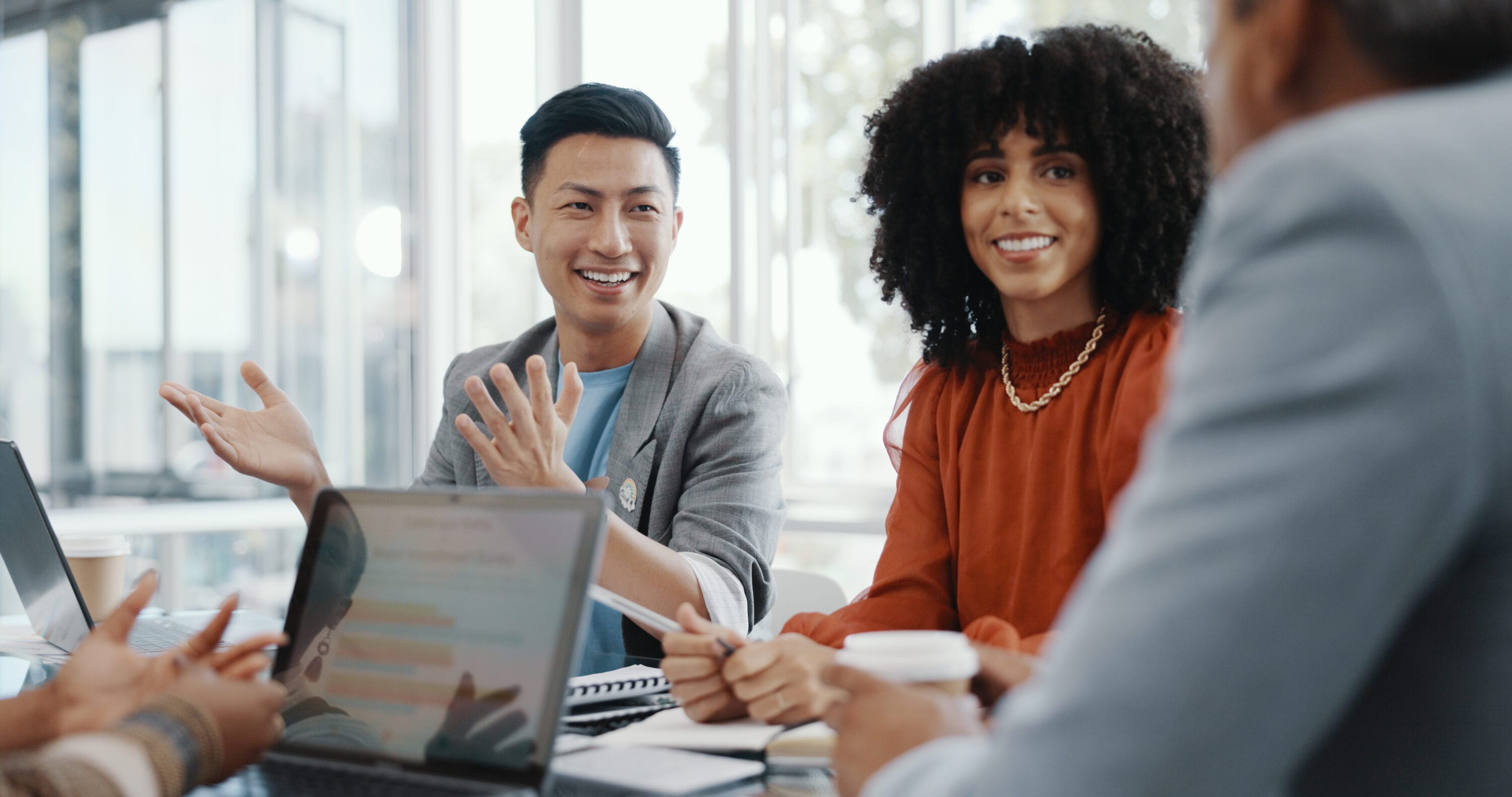 A group of young professionals speaking amongst each other in a meeting.