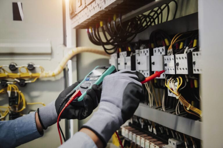 A pair of gloved hands working on electrical wiring.