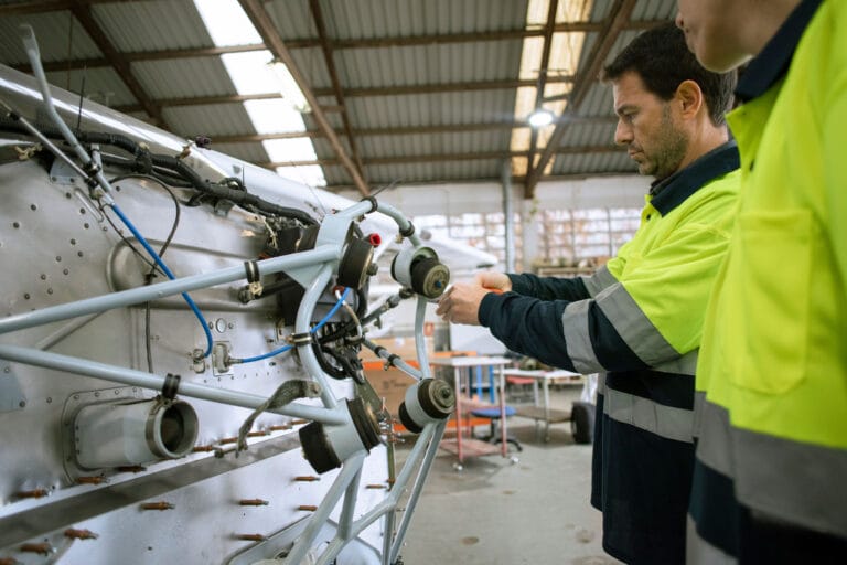 Two engineers in protective gear working on machinery.