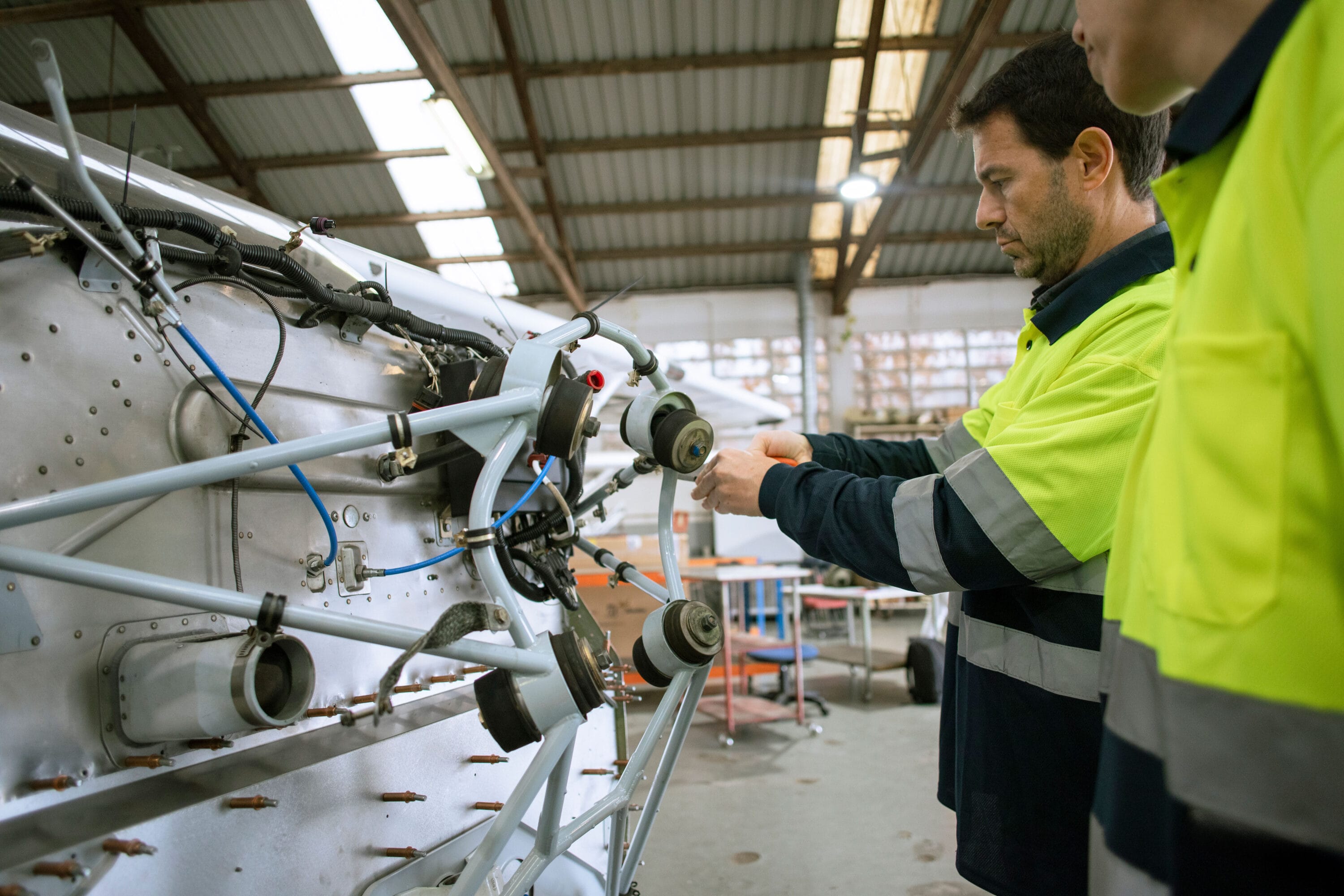Two engineers in protective gear working on machinery.