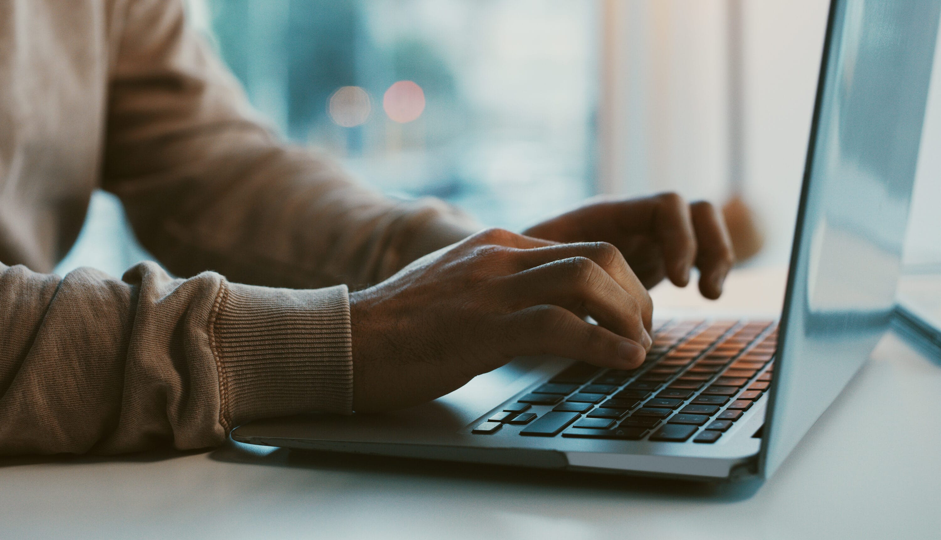 A pair of hands typing on a laptop.