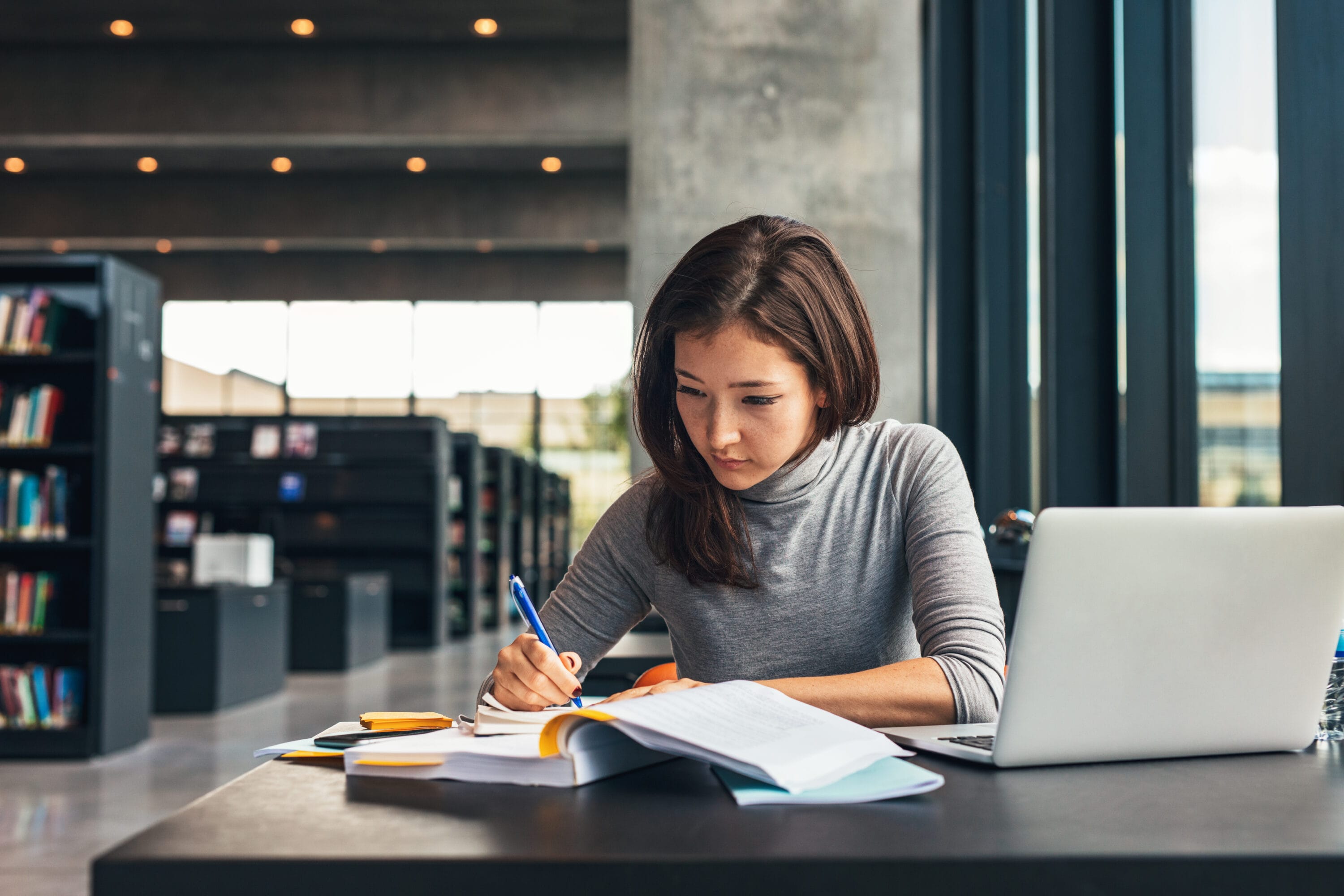 Woman in a library taking down notes.