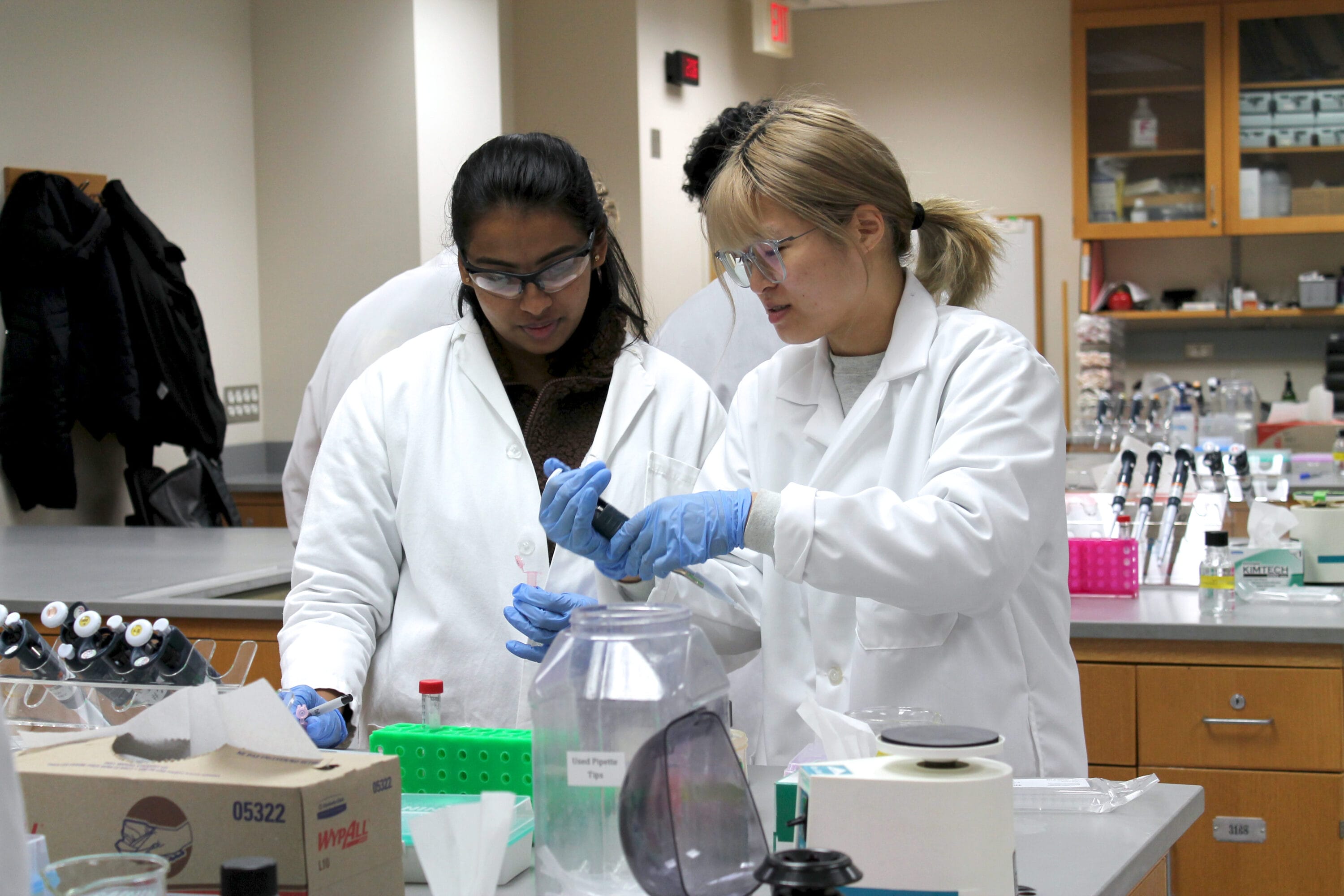 Two scientists in lab jackets working with test tubes.