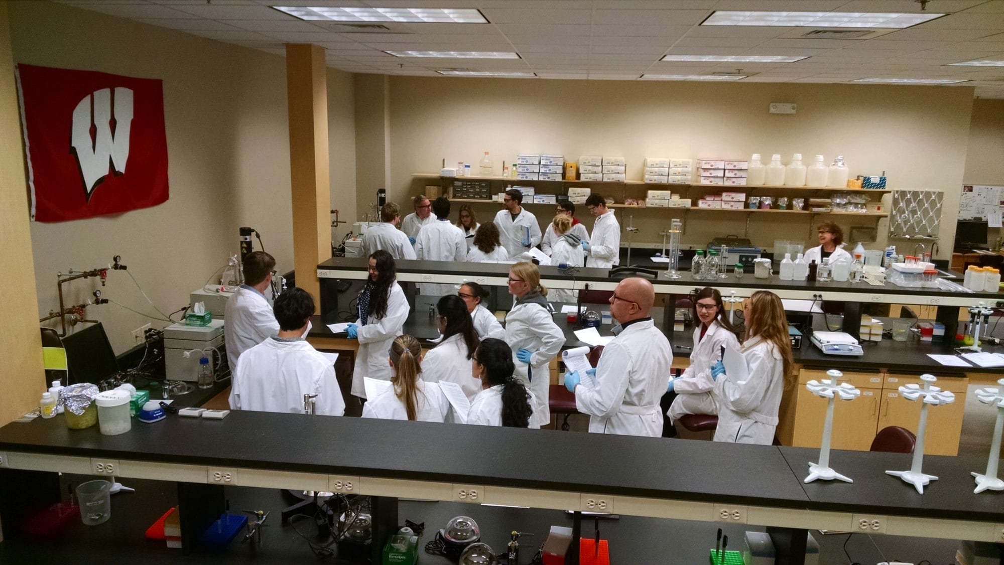 A group of scientists huddled around their instructor while attending class in a lab