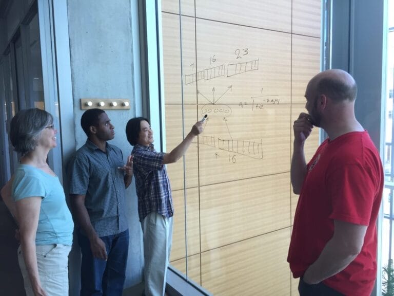 A machine engineering teacher leading a discussion with two of his students