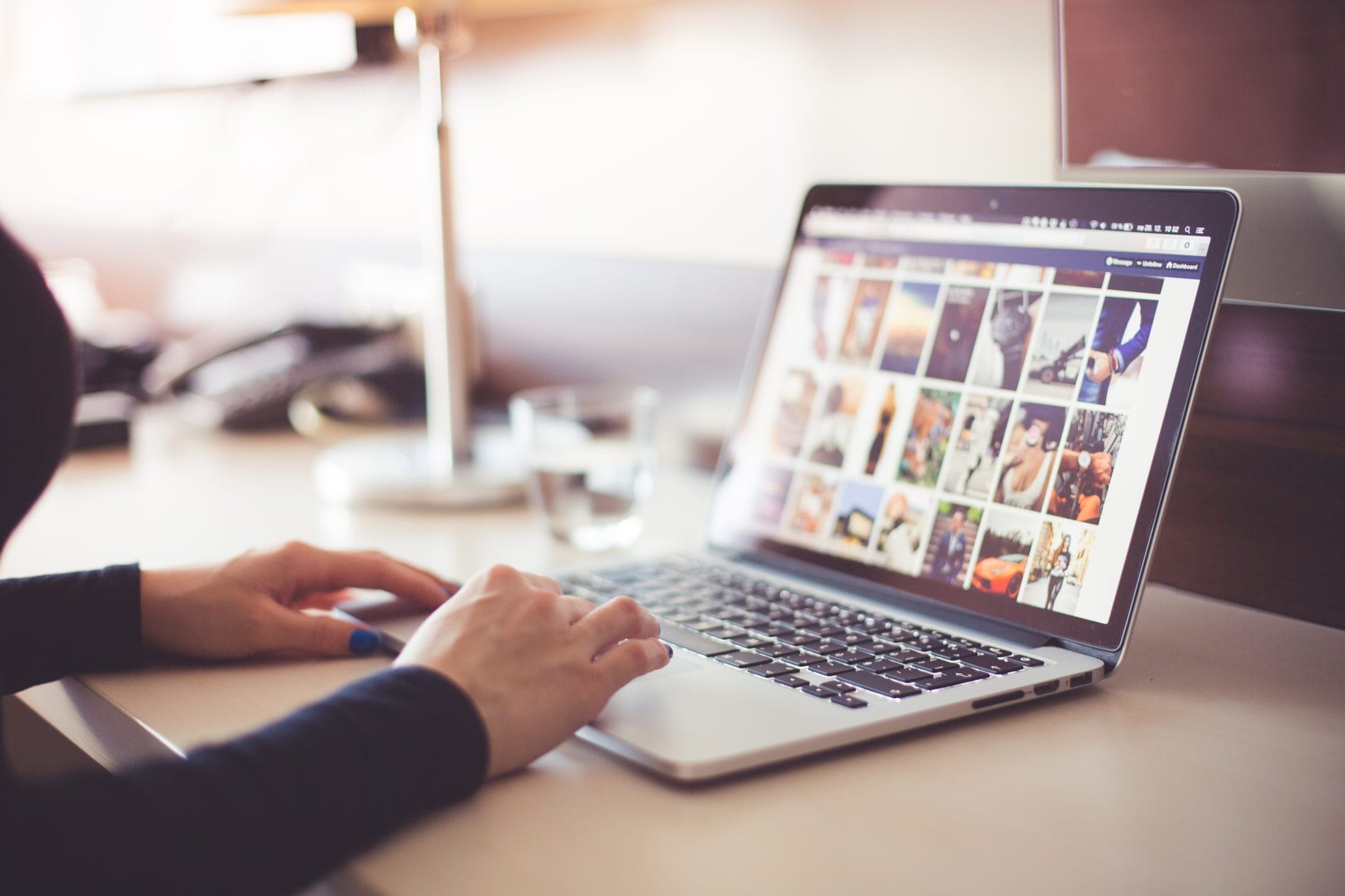 A pair of hands scrolling through some photos on their laptop