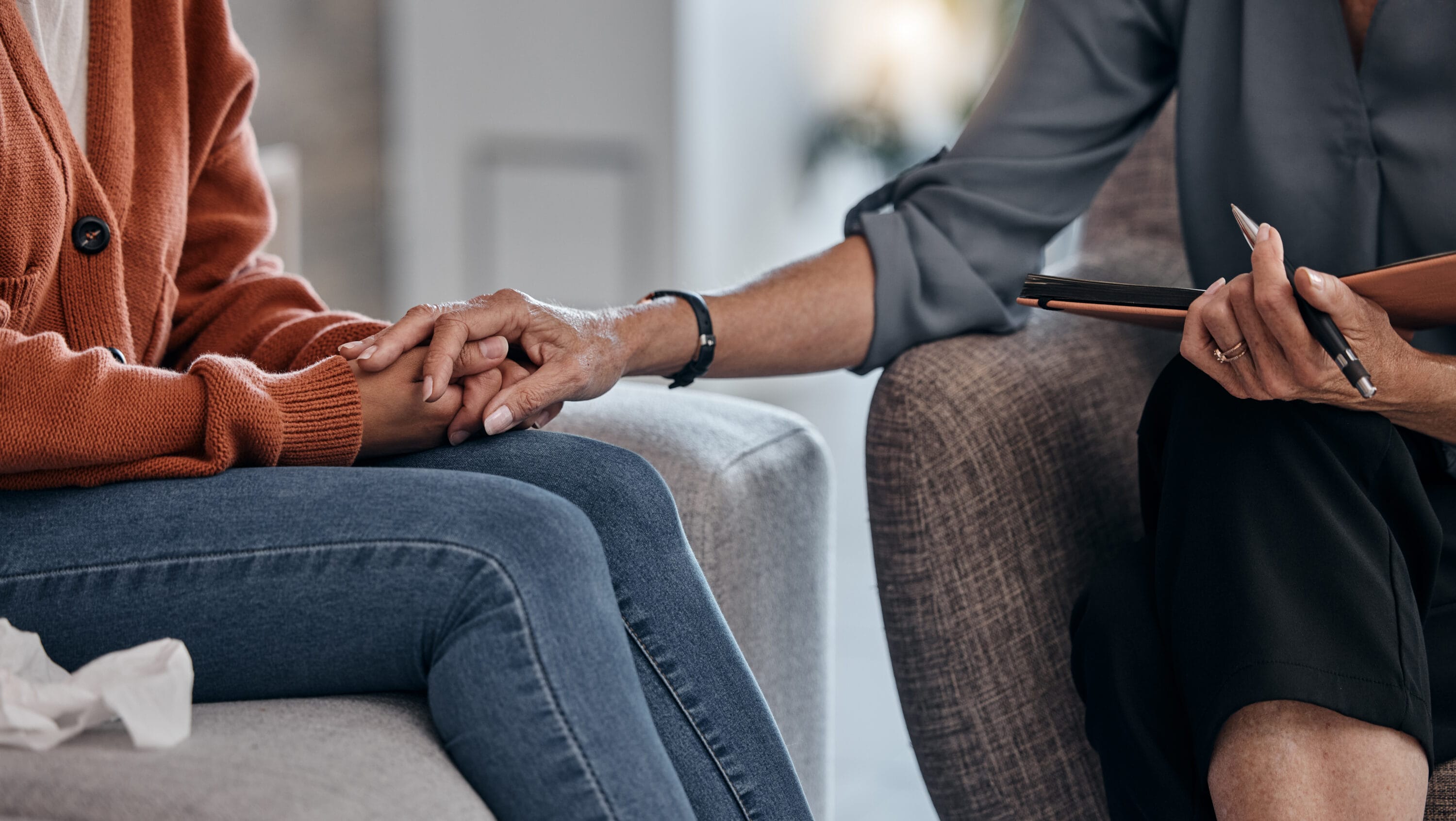 A closeup of a woman holding her therapists hands for comfort during a session