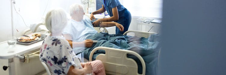 A medical professional taking an elderly man's pressure in a hospital room