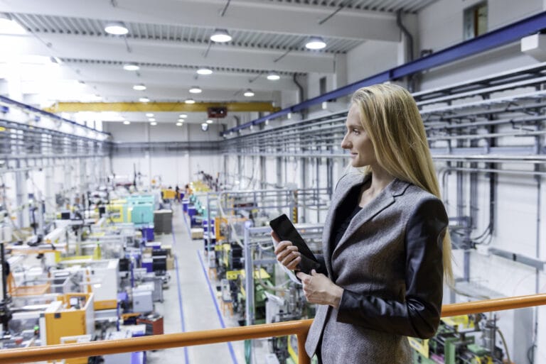 A woman standing in a ledge as she supervises a manufacturing plant floor