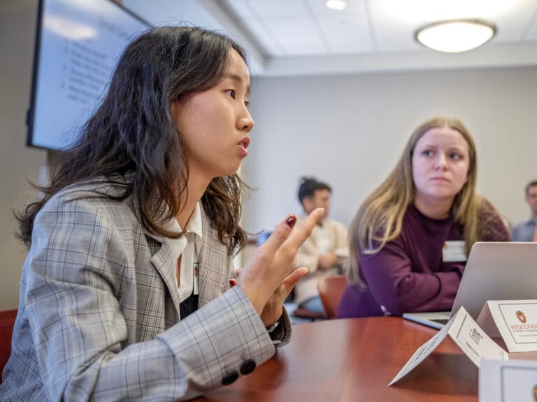 A woman dressed in business attire speaking to a small group of graduates