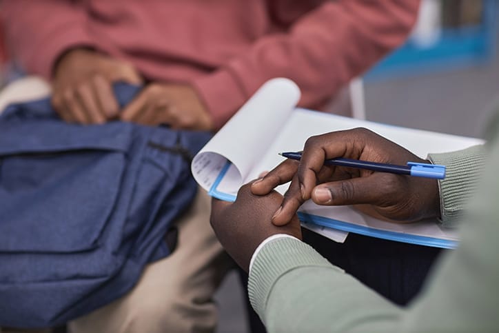 Closeup of a pair of hands resting on top of a clipboard