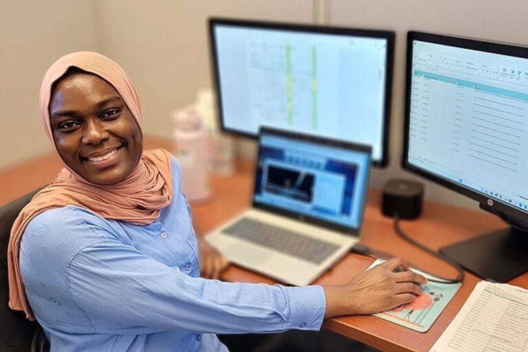 Fatima Abdul Rasheed smiling for a picture while at her desk.