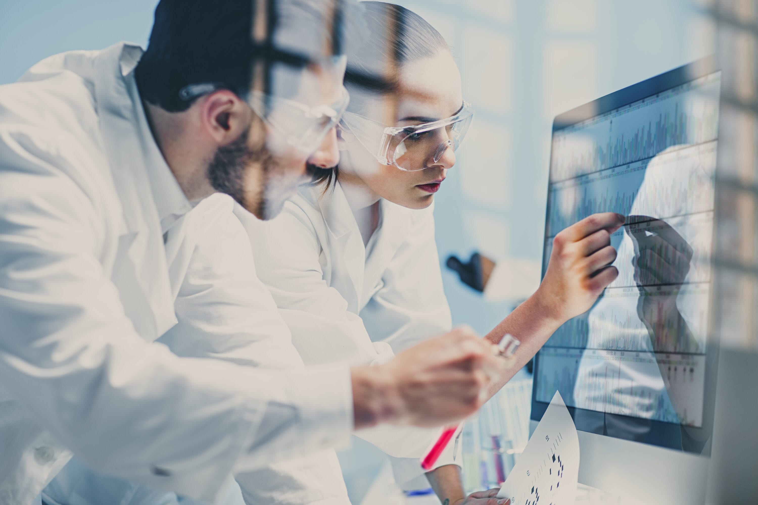 Two scientists in lab coats reviewing medical data.