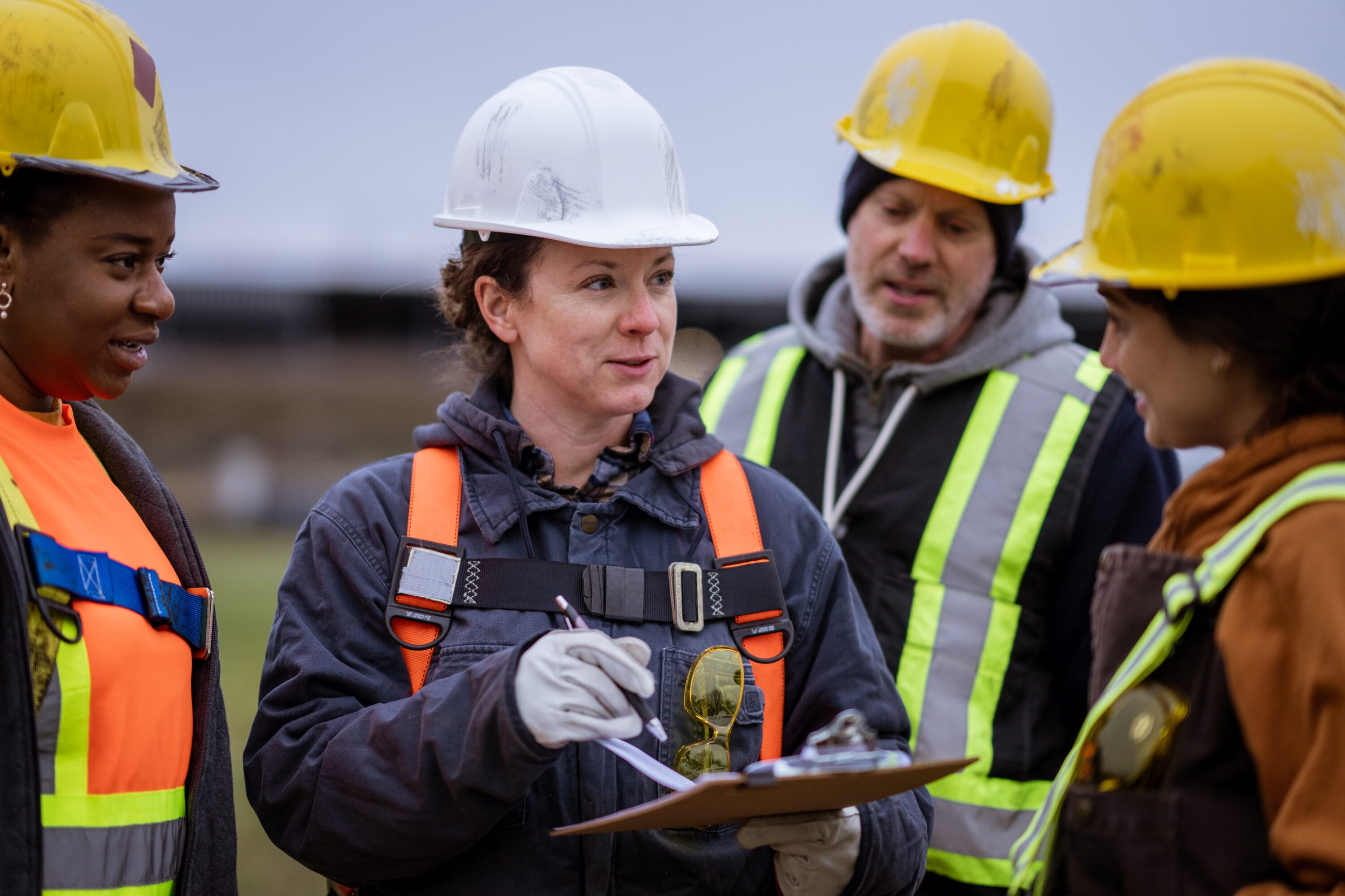 A group of workers in hardhats reviewing blueprints.