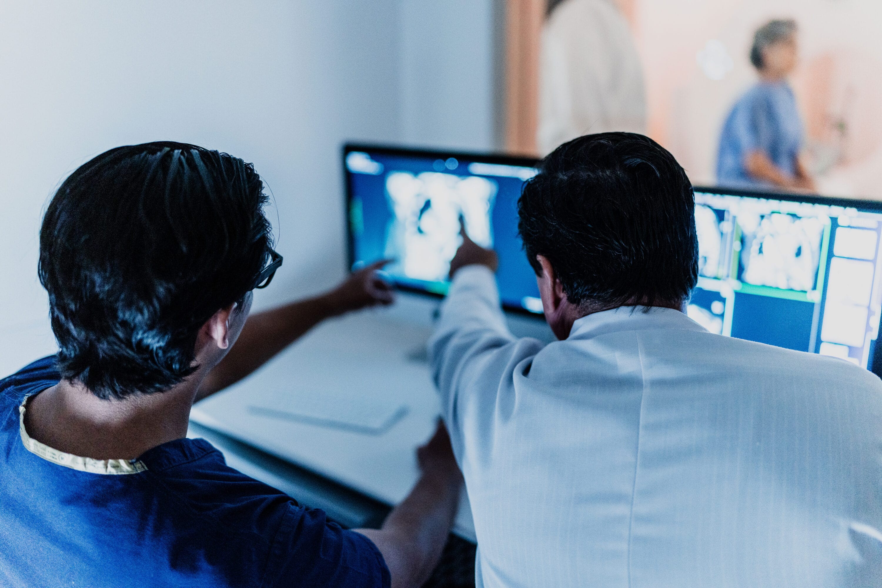 Two scientists reviewing medical images on a computer monitor.