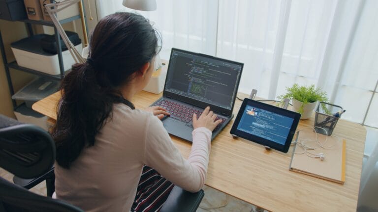 A woman on her laptop working on code.