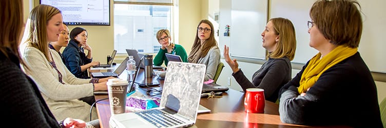 A group of PhD Nursing students have a discussion around a table.