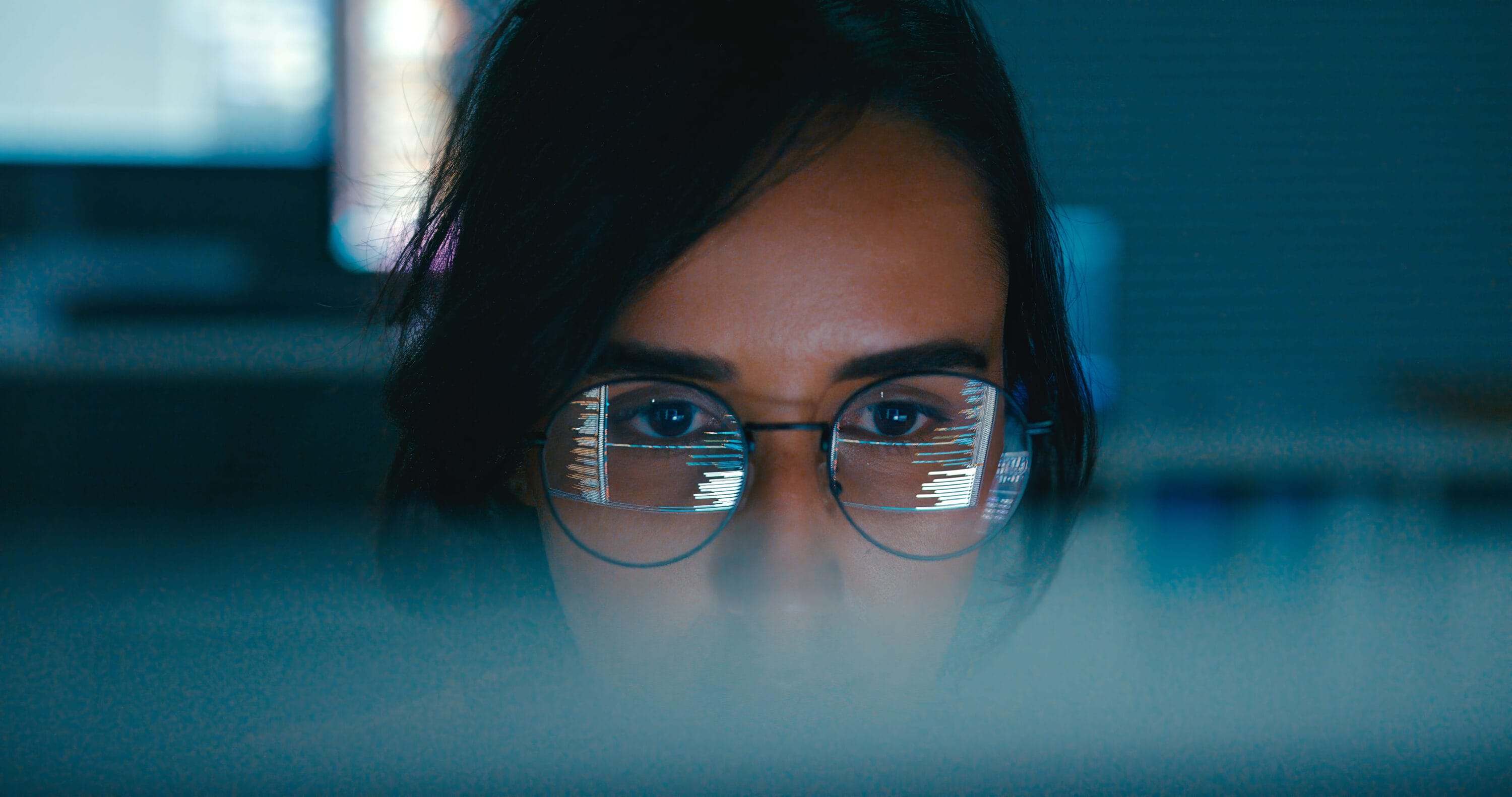 The upper half of a woman's face is visible as she works on her laptop.