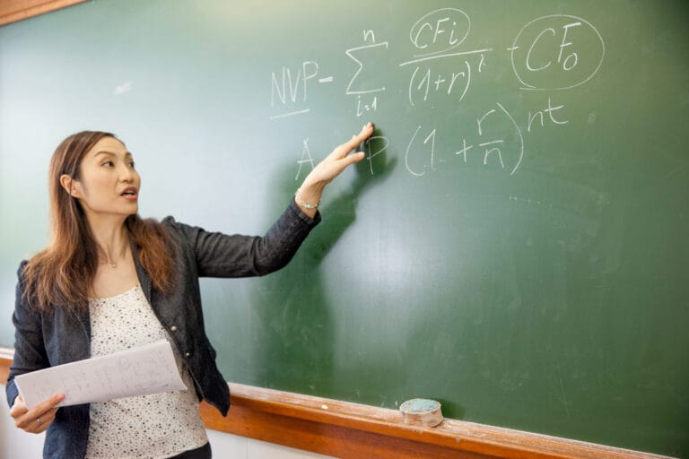 A woman reviewing mathematical equations on a chalkboard.