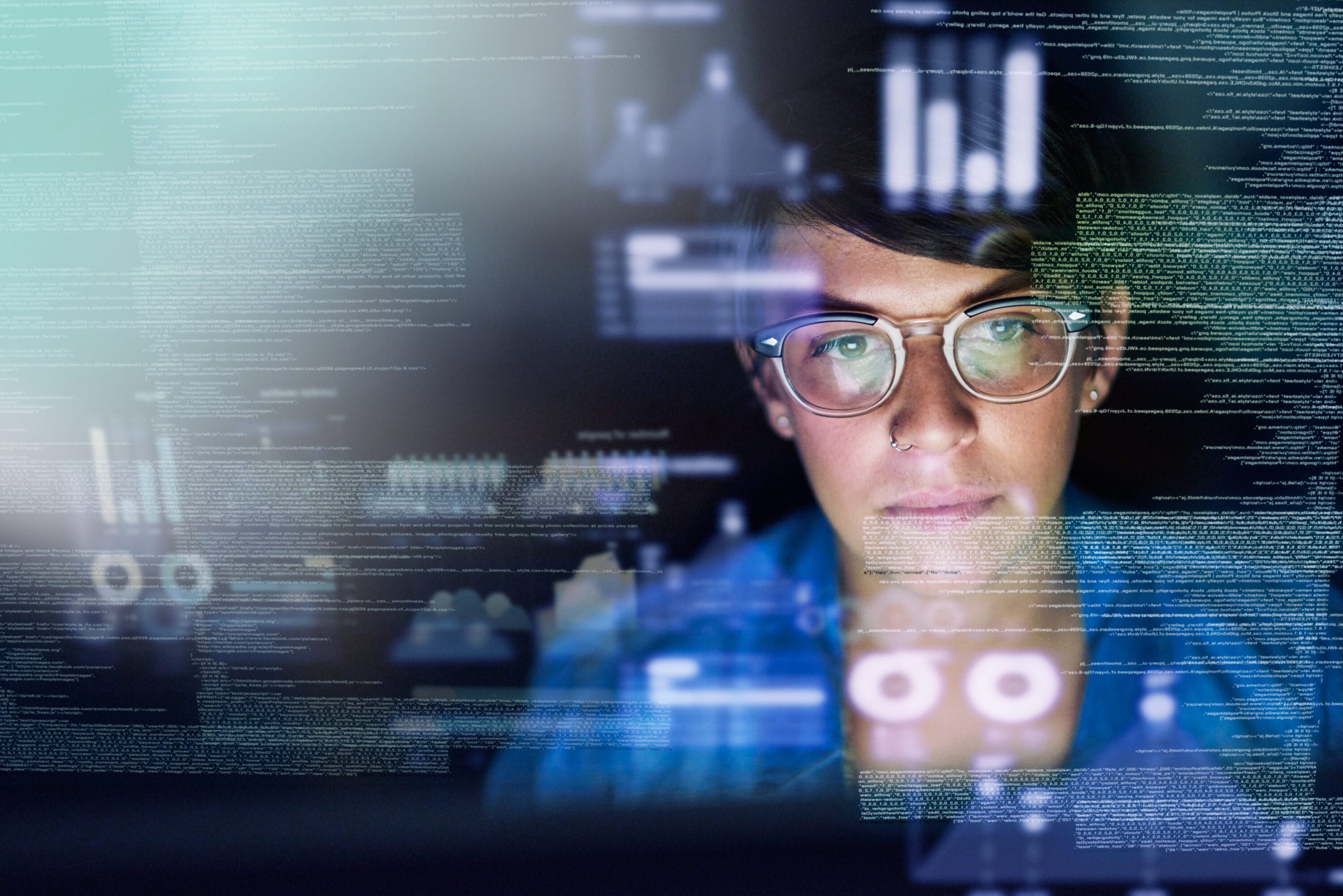 A woman working on her laptop. Before her, graphical visualizations are projected.