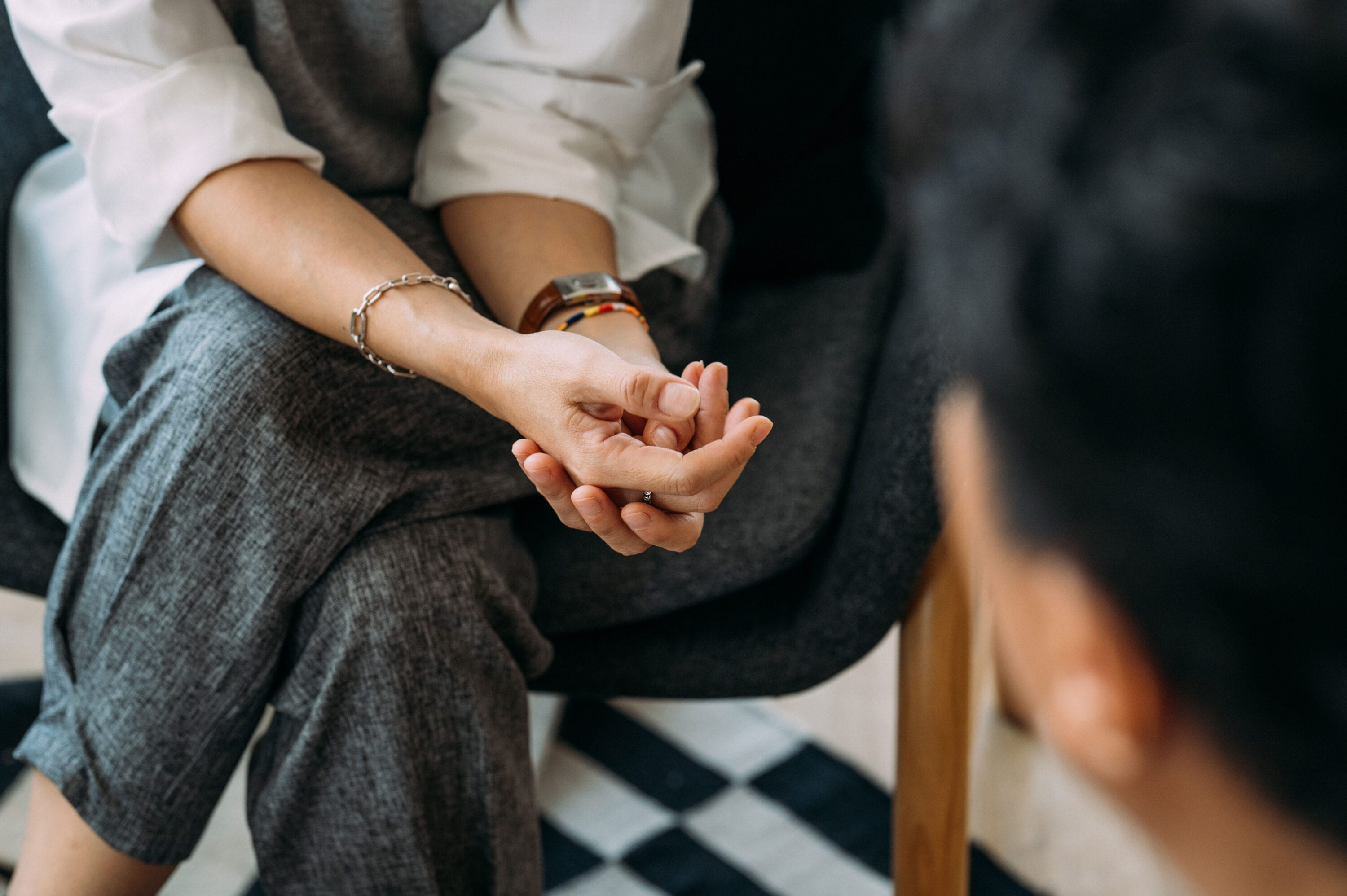 A person sitting in front of a patient with their hands folded.