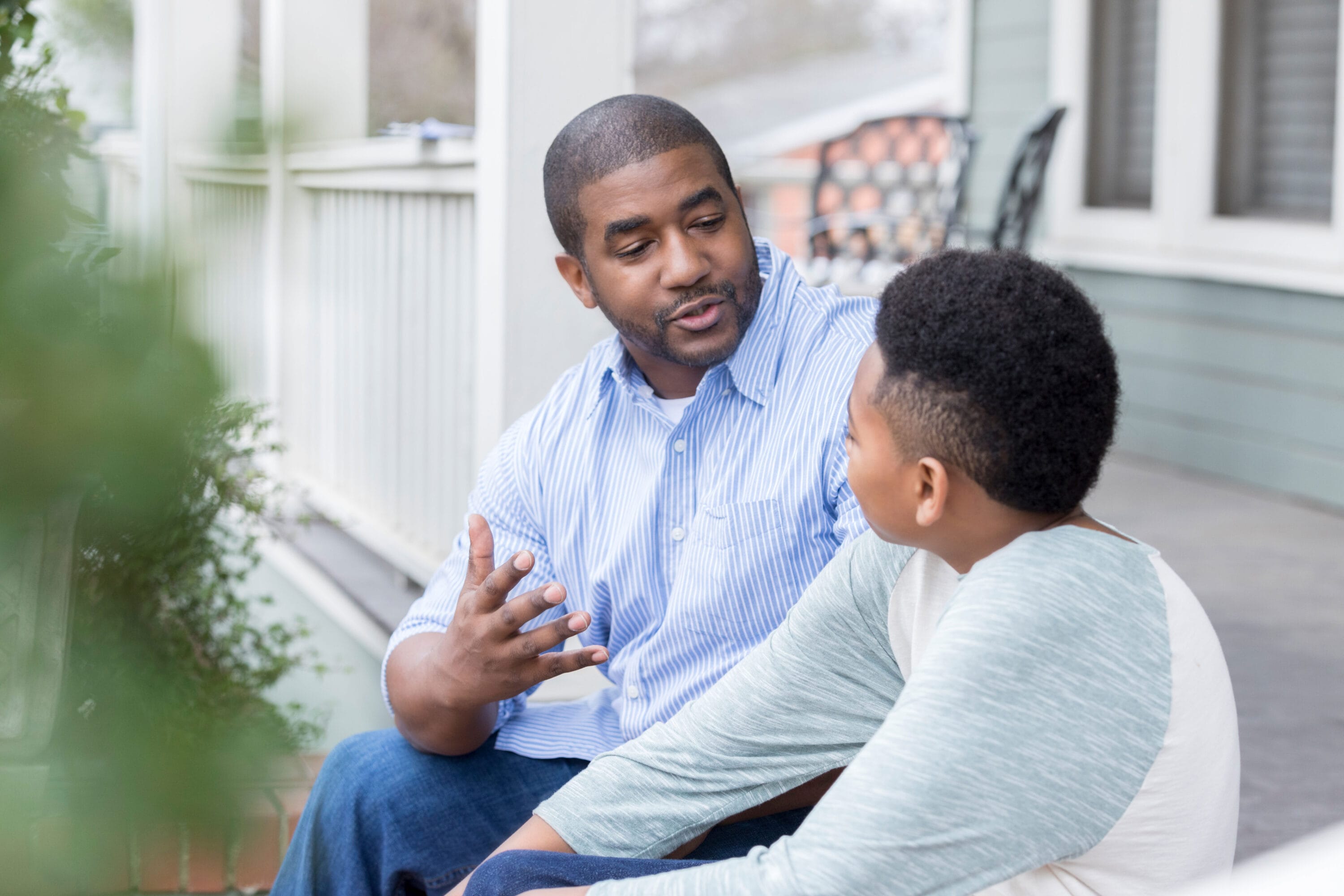 A man and child are sitting on some stairs, talking.