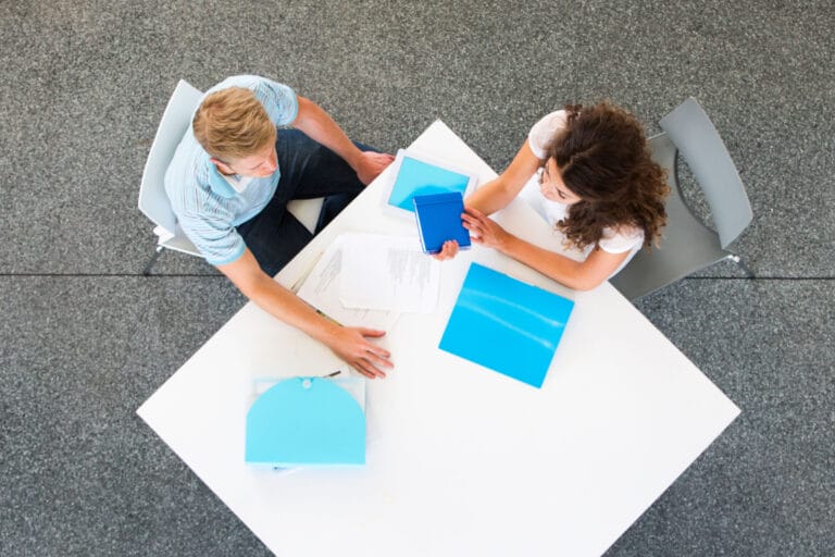 Two people talking and reviewing documents.