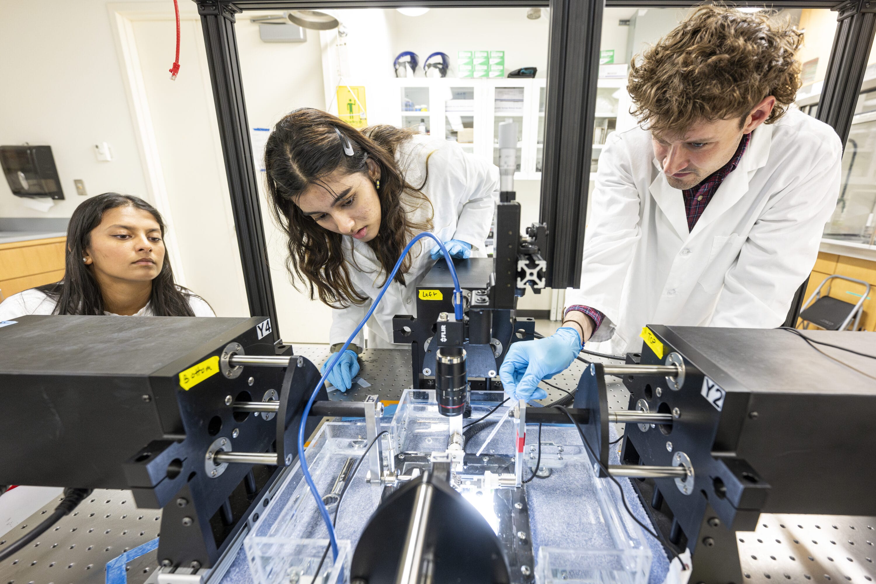 Three students working on biotech equipment.