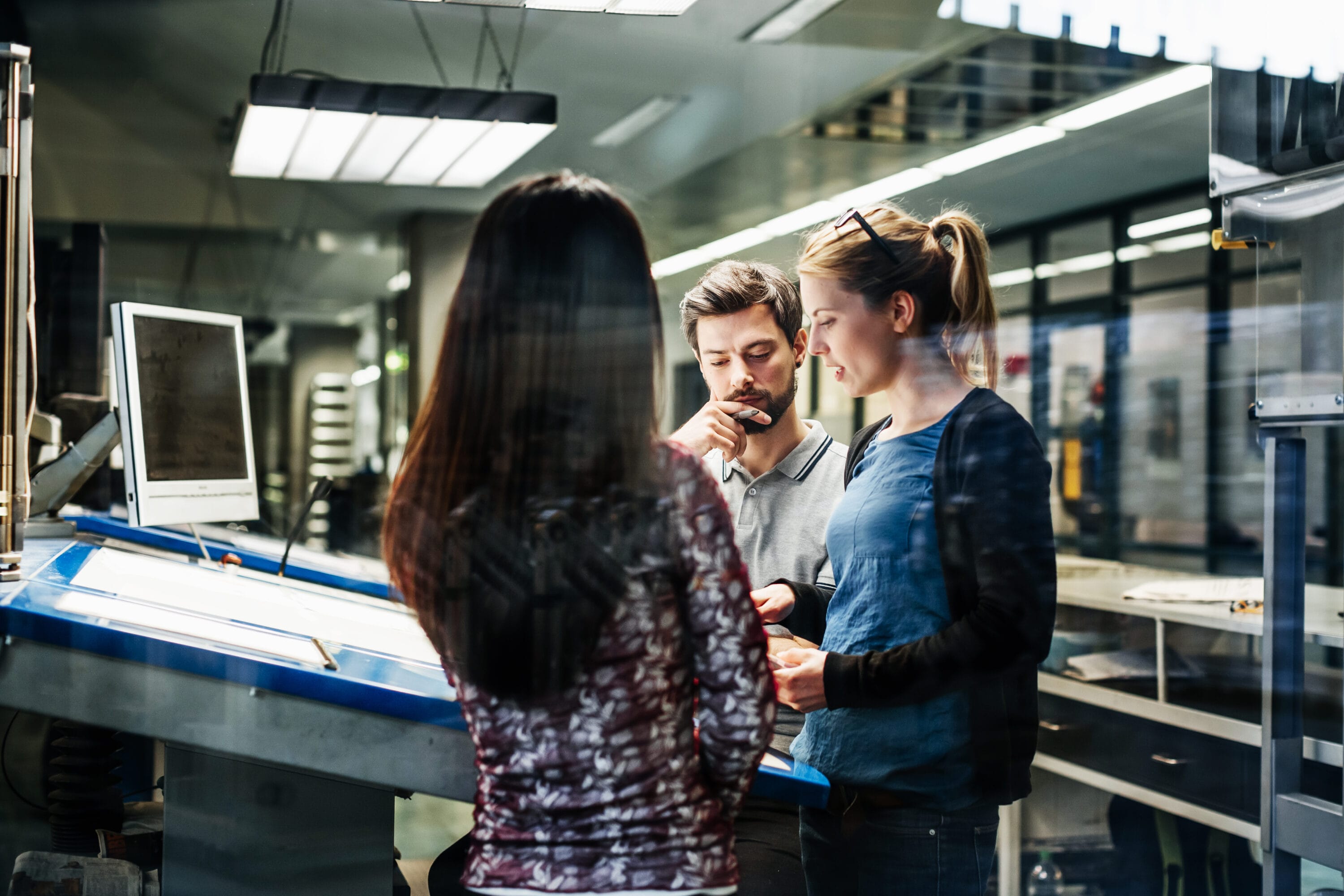 Two women and one man are in a room reviewing blueprints.